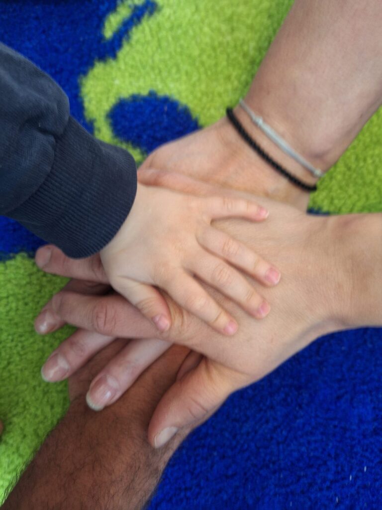 eine Gruppe von übereinander liegenden Händen - ein Kind und zwei Erwachsene