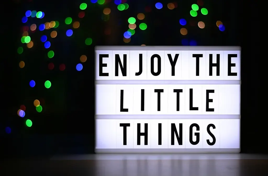 Zeigt eine Leuchttafel auf der steht "Enjoy the little things"