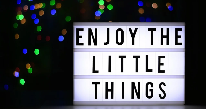 Zeigt eine Leuchttafel auf der steht "Enjoy the little things"