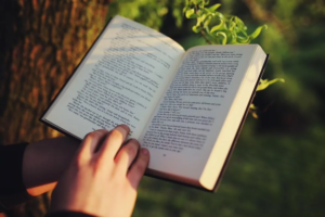 Zeigt ein aufgeschlagenes Buch mit einer Hand am unteren Ende