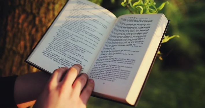 Glück zum Selbermachen – Anleitung ganz ohne Schere und Klebstoff 1 Zeigt ein aufgeschlagenes Buch mit einer Hand am unteren Ende